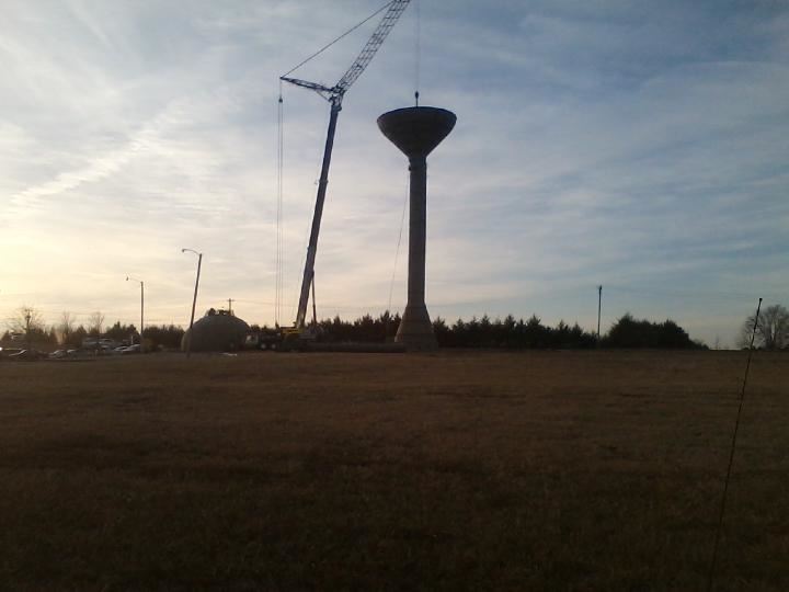 Crane setting the bottom of the water tank on top of the tower
